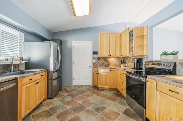 kitchen featuring backsplash, sink, stainless steel appliances, and vaulted ceiling