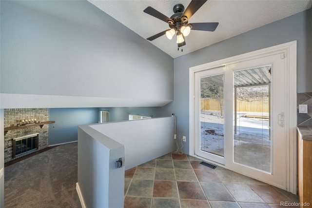 clothes washing area featuring ceiling fan, dark carpet, a textured ceiling, and a brick fireplace