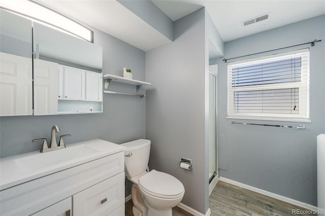 bathroom featuring a shower with door, vanity, wood-type flooring, and toilet