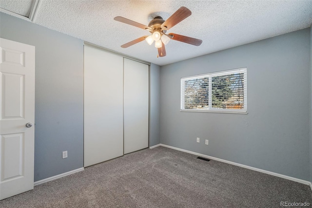 unfurnished bedroom featuring carpet, ceiling fan, a textured ceiling, and a closet