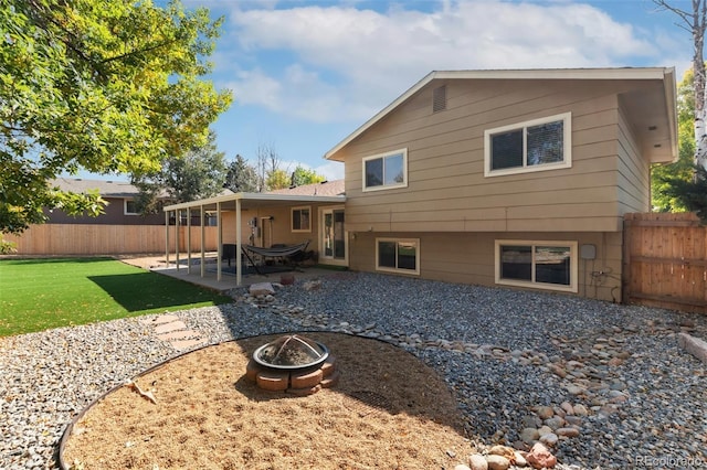 rear view of property featuring a lawn, an outdoor fire pit, and a patio