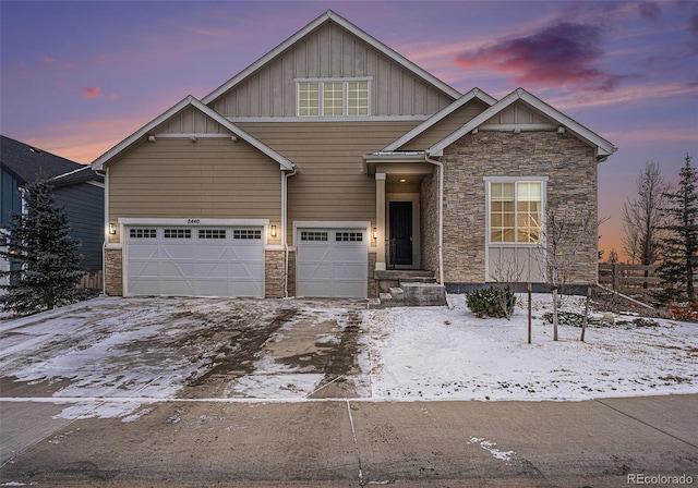 craftsman-style house with board and batten siding, stone siding, and driveway