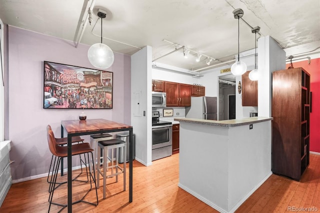 444 17th St Unit 603, Denver, CO 80202 - kitchen with hanging light fixtures, baseboards, light wood-style flooring, and stainless steel appliances