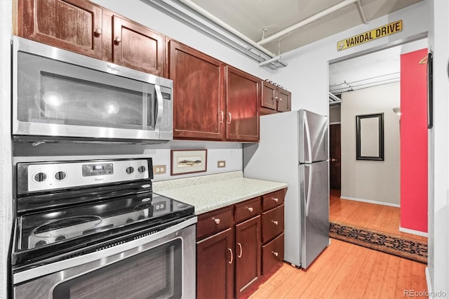 444 17th St Unit 603, Denver, CO 80202 - kitchen featuring baseboards, light countertops, stainless steel appliances, and light wood-type flooring