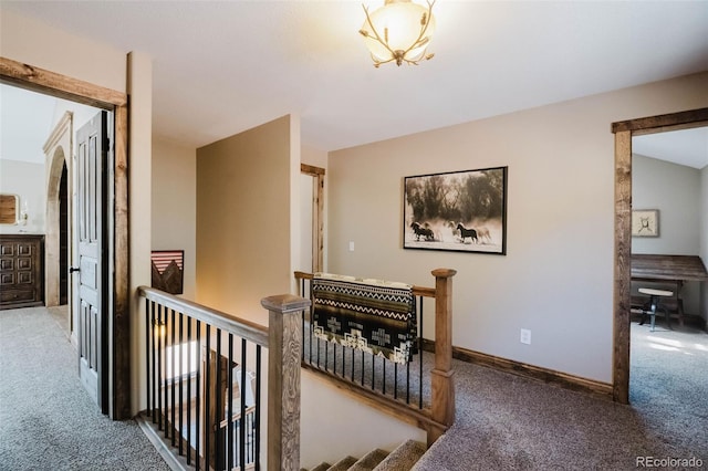hall with carpet flooring, an upstairs landing, and baseboards