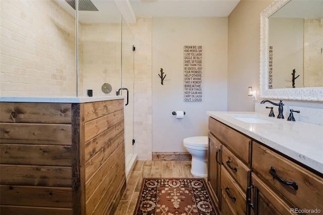 bathroom featuring a stall shower, vanity, toilet, and wood finished floors