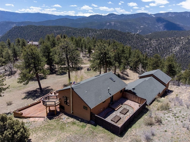 view from above of property with a mountain backdrop and a heavily wooded area
