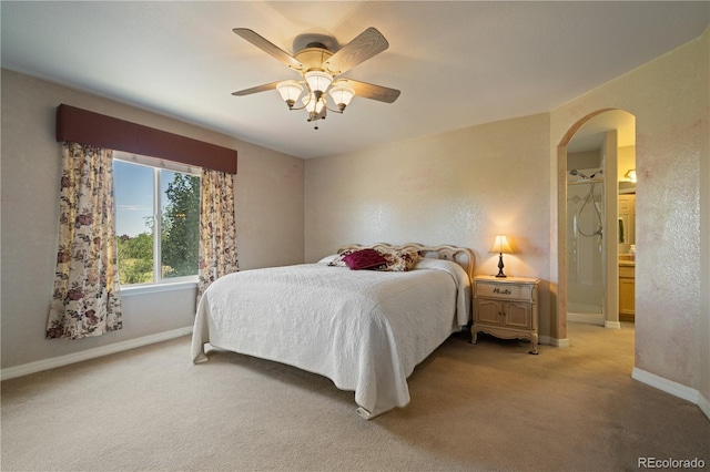 bedroom with baseboards, arched walkways, light colored carpet, and ceiling fan