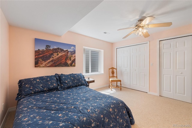 bedroom with a ceiling fan, carpet, multiple closets, and baseboards