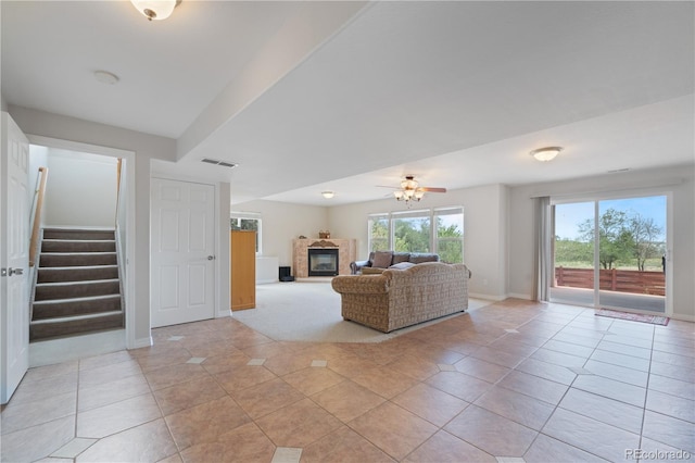 unfurnished living room featuring visible vents, a glass covered fireplace, stairway, light tile patterned floors, and baseboards