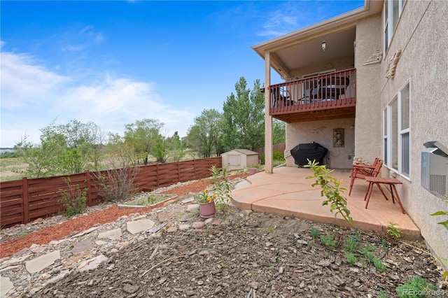 view of yard featuring a patio, a fenced backyard, a storage shed, an outdoor structure, and a balcony