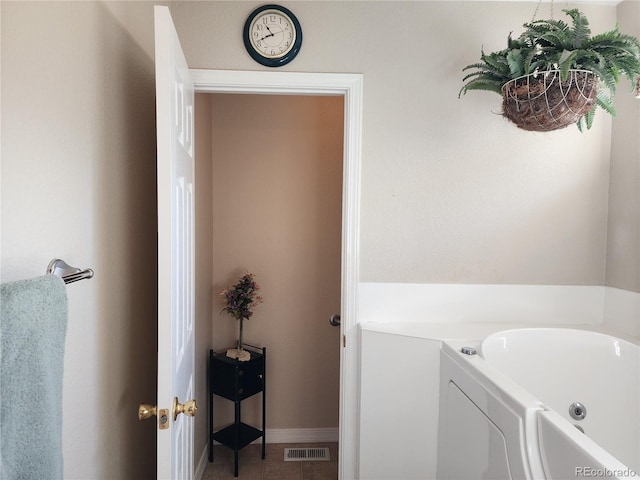 bathroom featuring a bath, visible vents, and baseboards