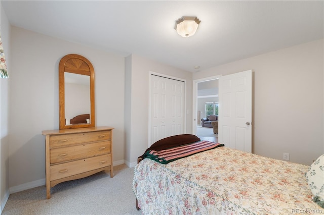 bedroom featuring a closet, light colored carpet, and baseboards