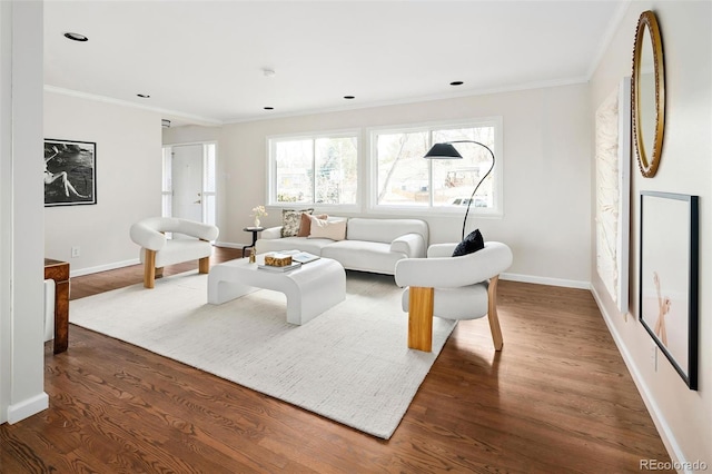 living area with ornamental molding, wood finished floors, and baseboards