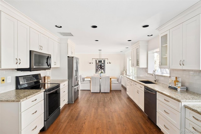 kitchen featuring stainless steel appliances, a sink, visible vents, white cabinetry, and glass insert cabinets