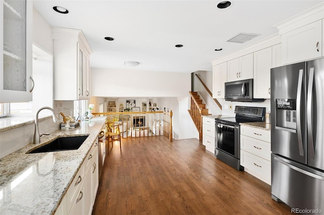 kitchen with dark wood-style flooring, visible vents, appliances with stainless steel finishes, white cabinets, and a sink