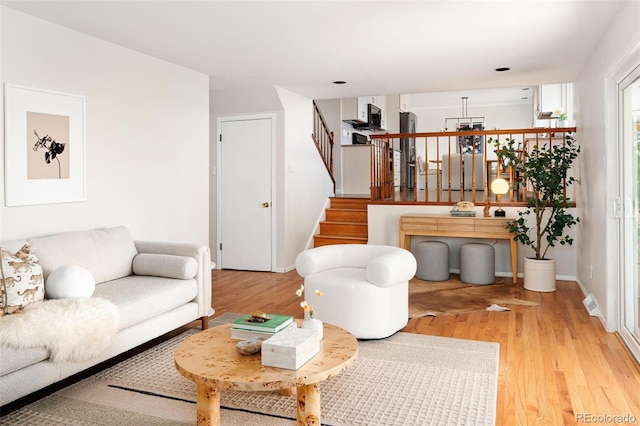 living room with stairs, baseboards, and wood finished floors