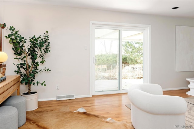 sitting room with light wood-type flooring, a healthy amount of sunlight, visible vents, and baseboards