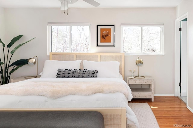 bedroom with multiple windows, wood finished floors, and baseboards