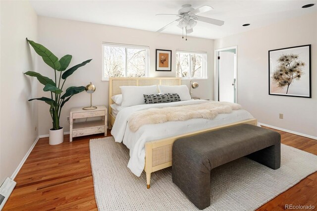 bedroom featuring ceiling fan, wood finished floors, visible vents, and baseboards