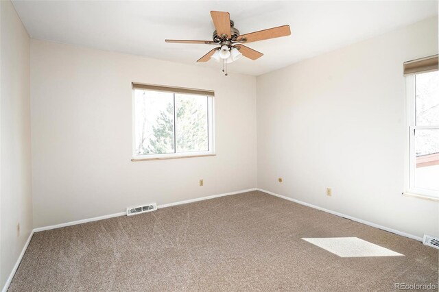 carpeted empty room featuring a ceiling fan, visible vents, and baseboards