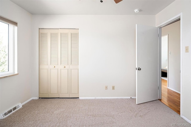 unfurnished bedroom with carpet, a closet, visible vents, and baseboards