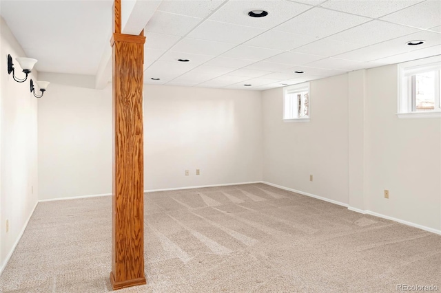 below grade area featuring a paneled ceiling, a healthy amount of sunlight, and carpet flooring