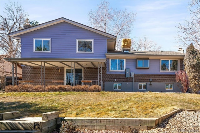 back of house with covered porch, a chimney, a lawn, and brick siding