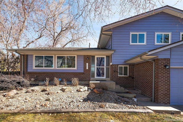 split level home featuring a garage and brick siding