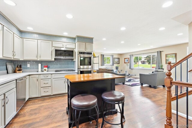13266 Canopus Dr, Lone Tree, CO 80124 - kitchen featuring stainless steel appliances, open floor plan, a breakfast bar, tasteful backsplash, and recessed lighting