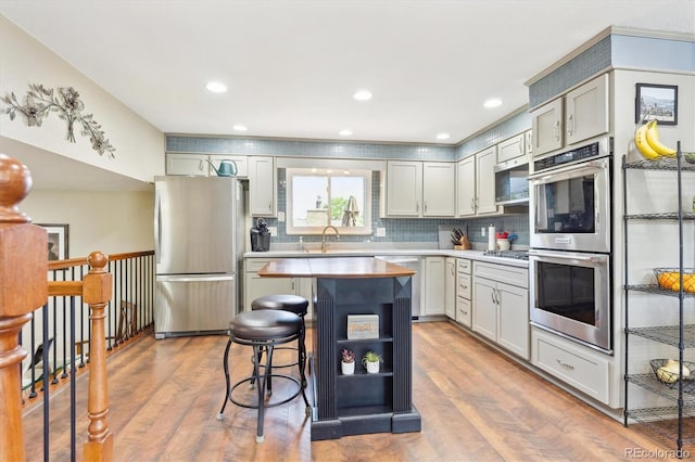 13266 Canopus Dr, Lone Tree, CO 80124 - kitchen with stainless steel appliances, light wood finished floors, a kitchen bar, a kitchen island, and backsplash