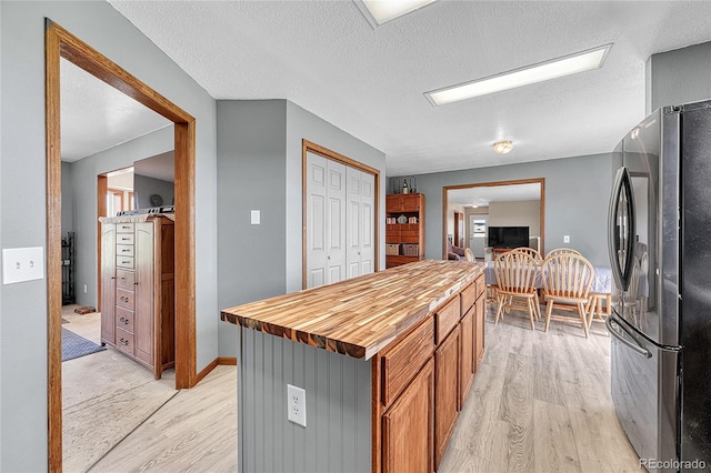 21494 Way Of Peace, Deer Trail, CO 80105 - kitchen featuring freestanding refrigerator, light wood finished floors, butcher block countertops, a kitchen island, and a textured ceiling
