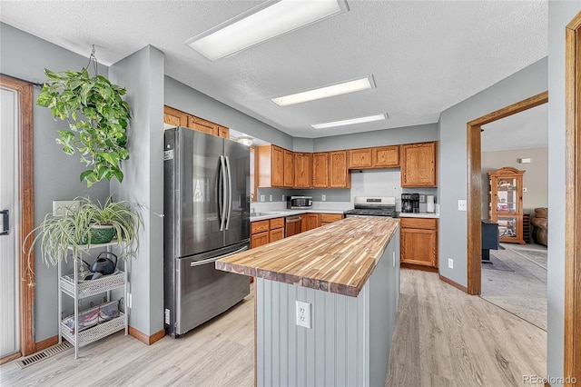 21494 Way Of Peace, Deer Trail, CO 80105 - kitchen with stainless steel appliances, light wood-style floors, butcher block counters, a textured ceiling, and brown cabinetry