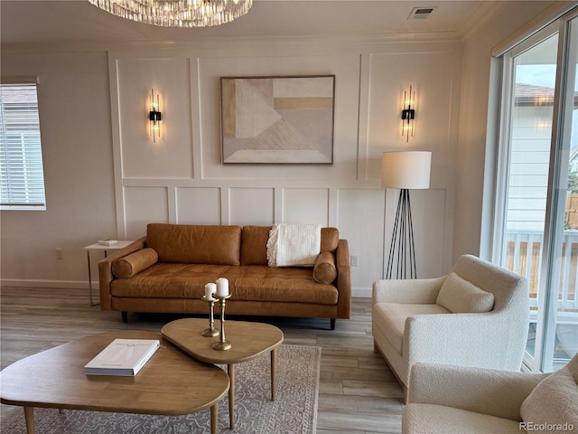 living area featuring light wood-type flooring, a decorative wall, and visible vents