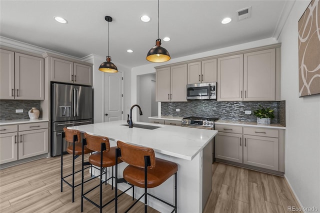 kitchen featuring a sink, stainless steel appliances, a kitchen breakfast bar, gray cabinetry, and decorative backsplash
