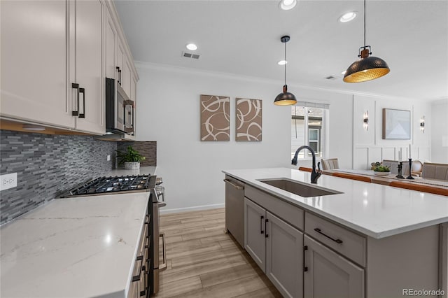 kitchen featuring a sink, tasteful backsplash, appliances with stainless steel finishes, crown molding, and light wood-style floors