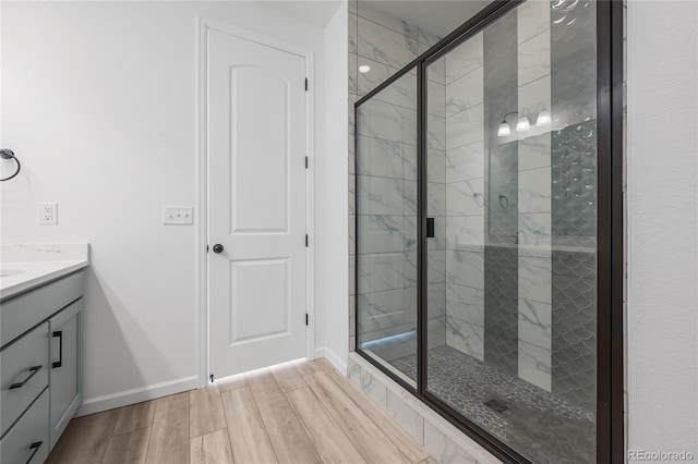 full bathroom featuring a stall shower, vanity, baseboards, and wood finished floors