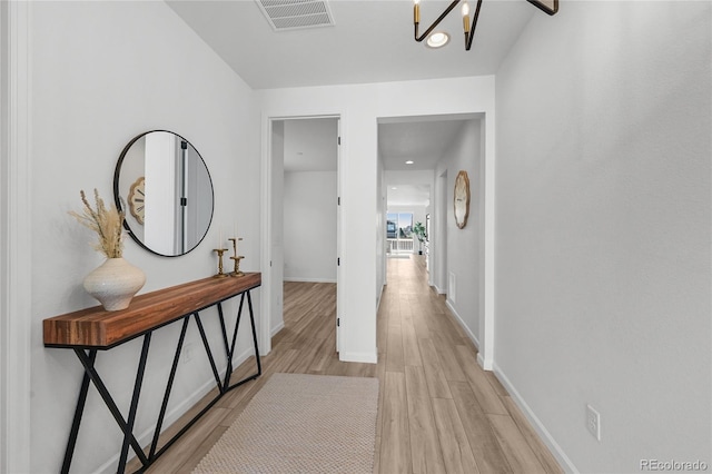 hallway featuring light wood finished floors, visible vents, baseboards, and recessed lighting