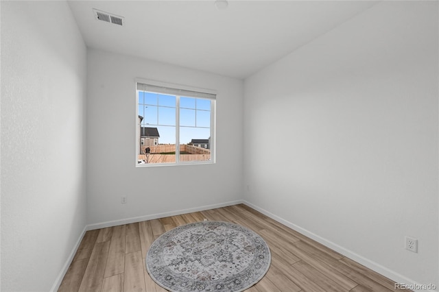 spare room with baseboards, light wood finished floors, and visible vents