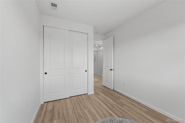unfurnished bedroom featuring baseboards, a closet, light wood-style flooring, and visible vents