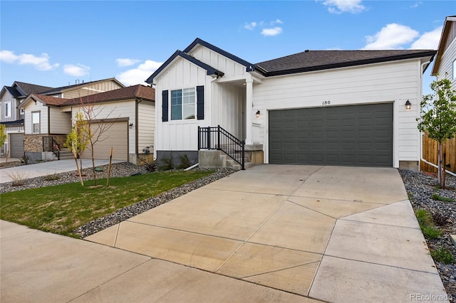 view of front facade featuring fence, an attached garage, driveway, a front lawn, and board and batten siding