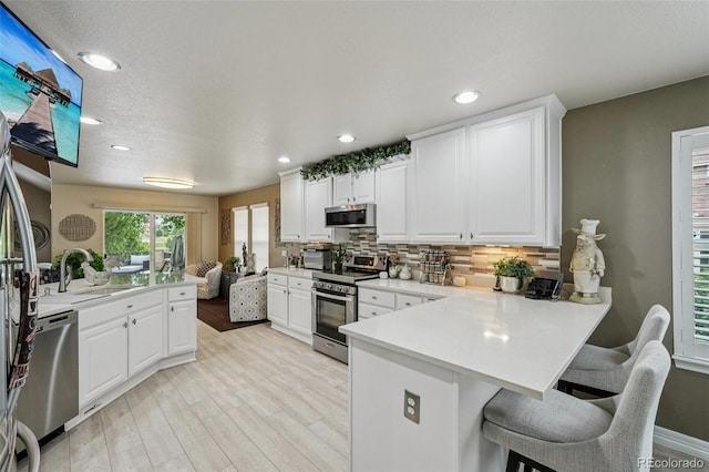 7548 S Biloxi Way, Aurora, CO 80016 - kitchen featuring stainless steel appliances, a peninsula, decorative backsplash, a kitchen breakfast bar, and light countertops