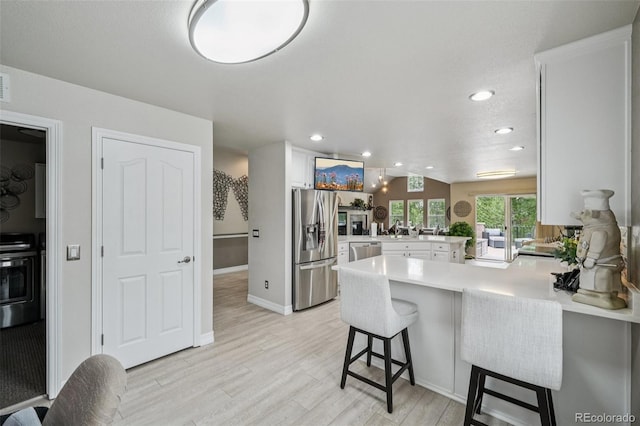 7548 S Biloxi Way, Aurora, CO 80016 - kitchen with stainless steel appliances, a peninsula, white cabinets, light countertops, and light wood-style floors