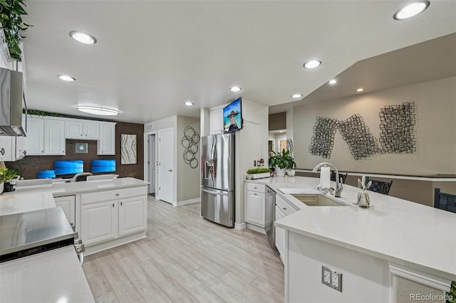 7548 S Biloxi Way, Aurora, CO 80016 - kitchen with stainless steel appliances, a peninsula, light wood-style flooring, white cabinets, and recessed lighting