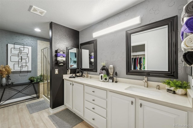 7548 S Biloxi Way, Aurora, CO 80016 - bathroom featuring wood finished floors, double vanity, and a stall shower