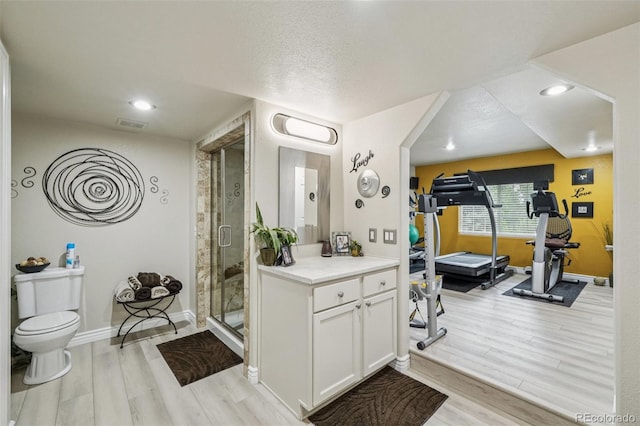 7548 S Biloxi Way, Aurora, CO 80016 - bathroom featuring wood finished floors, vanity, a shower stall, recessed lighting, and a textured ceiling