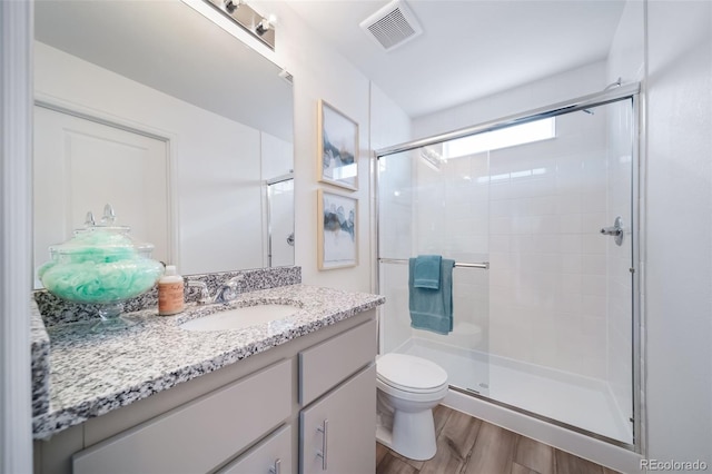 bathroom featuring hardwood / wood-style flooring, vanity, toilet, and walk in shower