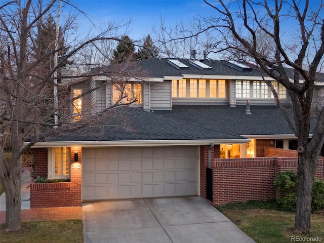 view of front of property featuring concrete driveway, brick siding, a shingled roof, and a garage