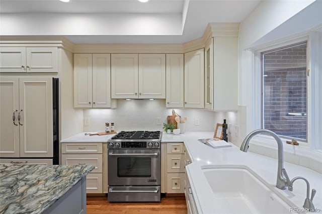 kitchen with gas range, a sink, decorative backsplash, wood finished floors, and recessed lighting