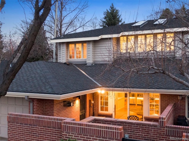 rear view of property with roof with shingles and brick siding